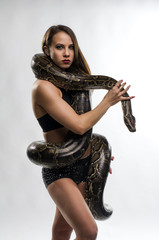 Beautiful gymnastics woman with python in studio