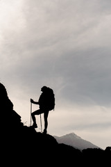 Silhouette of female hiker climbing up mountain