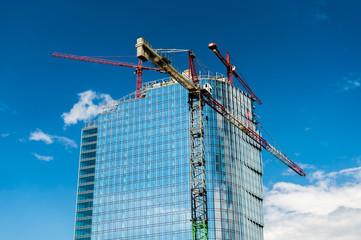 dźwig na tle wieżowca i nieba © FOTOWAWA