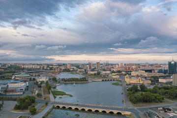 Fototapeta na wymiar South Ural capital Chelyabinsk; summer evening with cloudy sky; drone flying forward to city center over river, embankment zone; transportation system, recreation area, urban life in industrial city