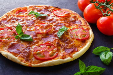 Homemade spicy pizza with sausage and tomato.