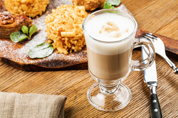 Cappuccino Cup with latte on wooden background. Beautiful foam, green ceramic Cup.