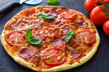 Homemade spicy pizza with sausage and tomato.