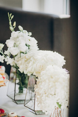 Stylish floral decor on wedding table. White roses and hydrangea flowers in glass vase on wedding centerpiece. Luxury catering and adorning