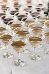 Martini rows on table at wedding reception. Cocktails and red and white martini in glasses at alcohol bar at wedding or christmas feast. Luxury catering