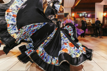 Beautiful gypsy girls dancing in traditional black floral dress at wedding reception in restaurant....