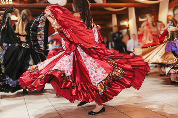 Gypsy dance festival, Woman performing romany dance and folk songs in national clothing. Beautiful roma gypsy girls dancing in traditional floral dress at wedding reception in restaurant - obrazy, fototapety, plakaty