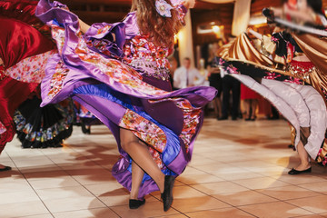 Beautiful gypsy girls dancing in traditional purple floral dress at wedding reception in...