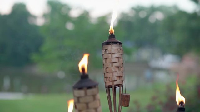 Tiki torches outside on a warm Summer evening, burning and gently blowing in the breeze at 120 frames per second.