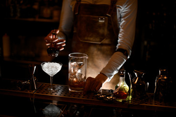 Male bartender pouring an essence from the little glass bottle
