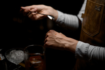 Male bartender holding a spoon and put a drop on the hand