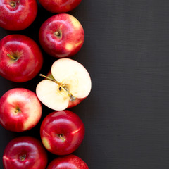 Naklejka na ściany i meble Overhead view, fresh raw red apples on a black background. Flat lay, top view, from above. Copy space.