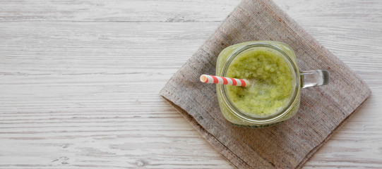 Green celery smoothie in a glass jar, overhead view. Flat lay, from above, top view. Space for text.