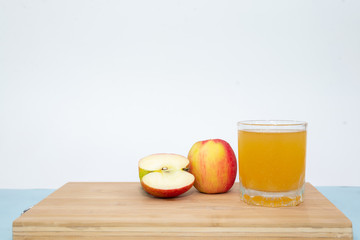 glass of apple juice and apple on wooden table on white background