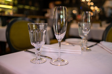 Natural light or daylight shot of modern restaurant table set for a lunch. Shallow focus on wine glass. Empty glasses set in restaurant.