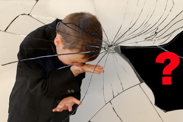 reflection in shards of a broken mirror, a crying boy, a junior schoolboy, is standing in the...