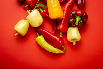 Yellow and red paprika on red background top view