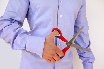businessman in a blue shirt holds in his hand open large stationery scissors