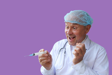 male doctor in a white coat and cap holds in his hand a medical rubber syringe, smiles recklessly,...