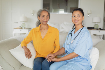 Obraz premium Healthcare worker and woman sitting on couch
