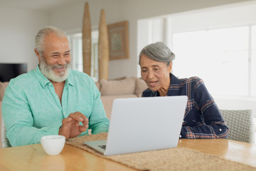 Couple using laptop on table inside a room