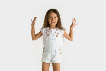 Beautiful female half-length portrait isolated on white studio background. Little emotional asian girl wearing white. Facial expression, human emotions, advertising concept. Surprised, happy.