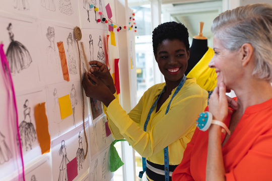 Female fashion designers discussing over sketch design