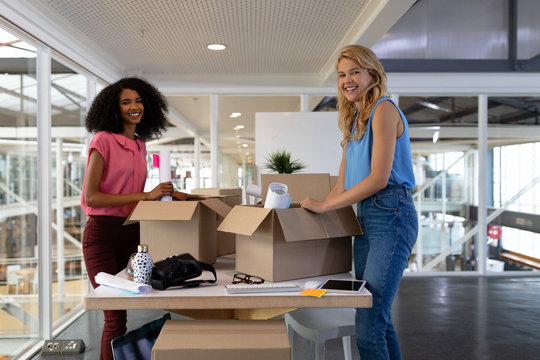 Female executives unpacking cardboard boxes in office