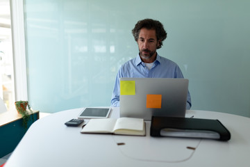 Businessman working on laptop at desk in office