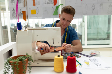 Male fashion designer using sewing machine on a table