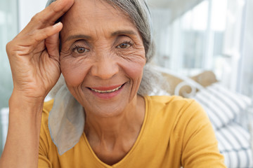 Woman inside a room with hand on the forehead and smiling