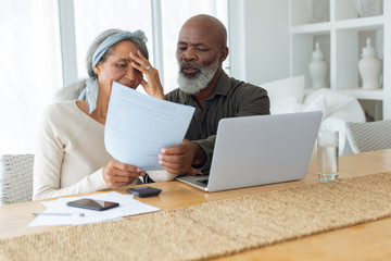 Couple discussing papers and using laptop inside a room