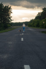 girl walking with a small dog on the road, walk with a dog in the country,