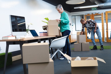 Male and female executives unpacking cardboard boxes in office
