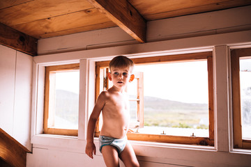 Little caucasian boy standing at window 