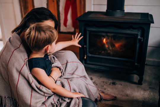 woman and toddler son sitting in front of fireplace