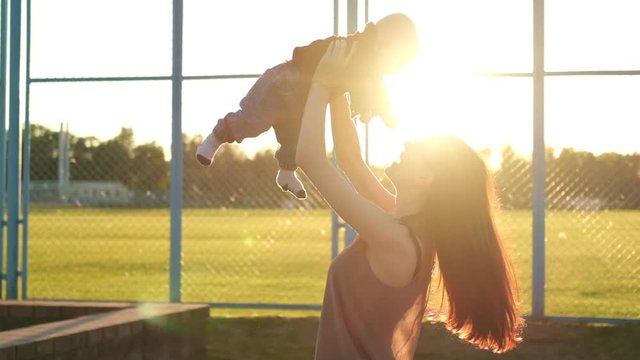 Mother plays with son near field at sunset. Slow mo