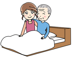 ベッドに寝ている老人男性をサポートする介護士の女性