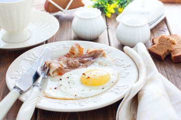Traditional English breakfast of fried eggs with bacon on a wooden table, horizontal
