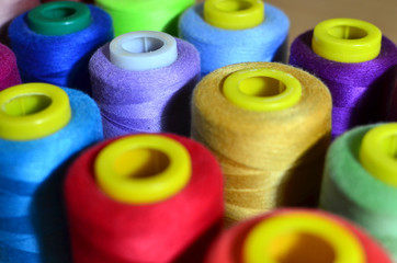 Background of bobbins with multicolored threads for sewing. Needlework, sewing and tailoring concept. Fabric and textile industry