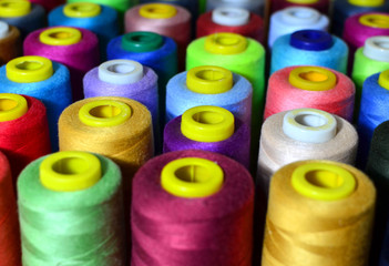 Background of bobbins with multicolored threads for sewing. Needlework, sewing and tailoring concept. Fabric and textile industry