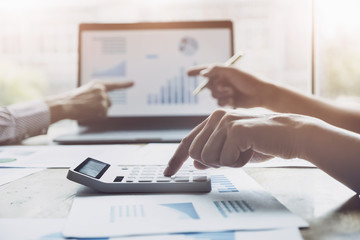 Business and partnership  discussing using calculator to review balance sheet annual with holding pen and using laptop computer to calculating budget. audit integrity before investment concept.