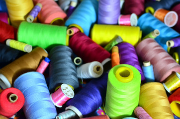 Background of bobbins with multicolored threads for sewing. Needlework, sewing and tailoring concept. Fabric and textile industry