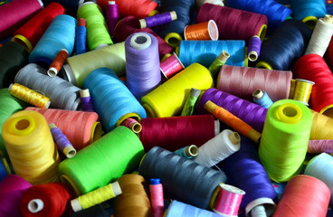 Background of bobbins with multicolored threads for sewing. Needlework, sewing and tailoring concept. Fabric and textile industry