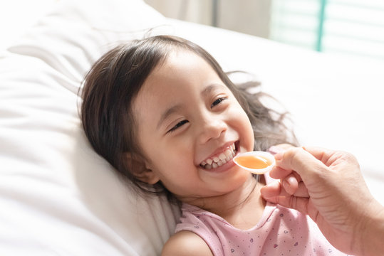 Happy asain girl taking medicine syrup from her mother