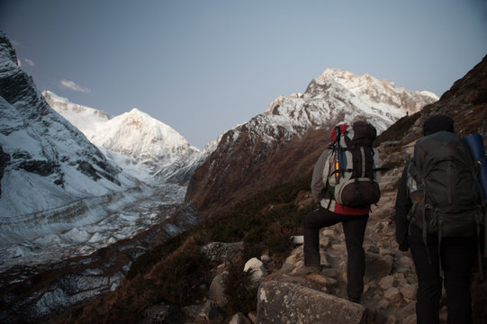 Young woman and man with backpacks walking to the pass on Manaslu circuit with view of Mount Manaslu range 8 156 meters. Trekkers in Himalayas, Manaslu Glacier in Gorkha District, Nepal. Sunny day.