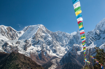 View of snow covered range of Mount Manaslu and prayer flags 8 156 meters with clouds in Himalayas, sunny day at Manaslu Glacier in Gorkha District in northern-central Nepal. 