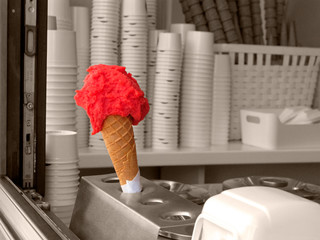 Strawberry or watermelon ice cream in a waffle cone in an ice-cream shop.