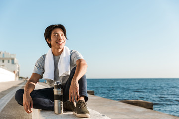Smiling young asian sportsman resting