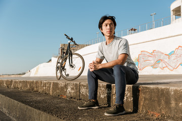 Young asian man bicyclist sitting at the seaside